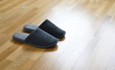 Ahşap zeminde gri terlikler.