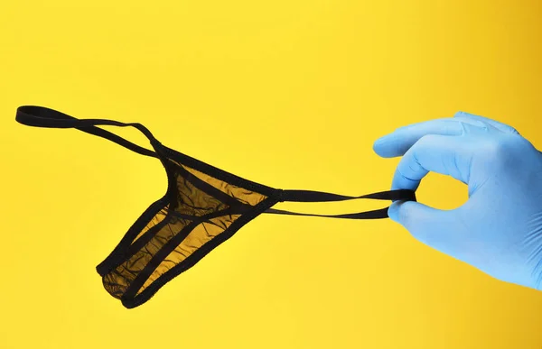 Hand Blue Rubber Glove Holds Black Thong Panties Yellow Background Stockbild