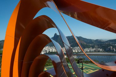 Rio de janeiro Brazil. May 24, 2022: Metal sculpture symbol of the Sugar Loaf park and cable car framing the view of the city from Urca Hill. In the background the mountains and Christ.