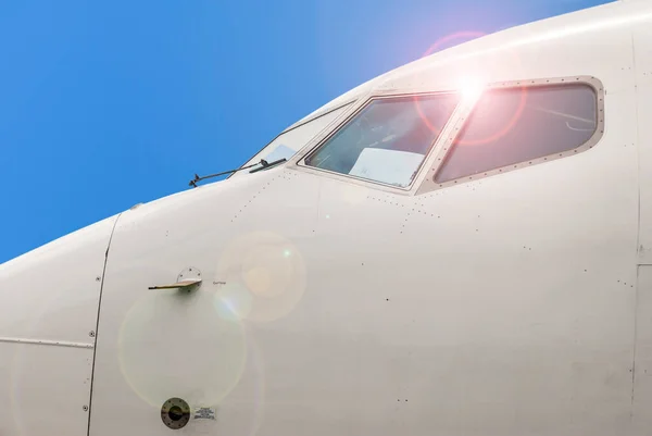Airplane. Front section. Large commercial airliner cabin windows and bodywork sensors. Blue sky clouds background. 