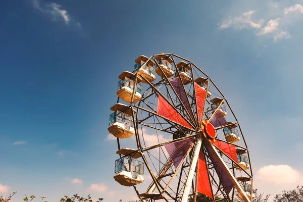 Colorful red and purple ferris wheel and blue sky in background