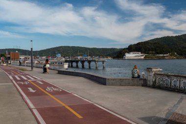 Santos, Sao Paulo, Brazil. - March 25, 2021: Seafront of the city of Santos in the Ponta da Praia region. Bike path, sidewalk, traditional city wall, fisherman's deck and the Barra fortress