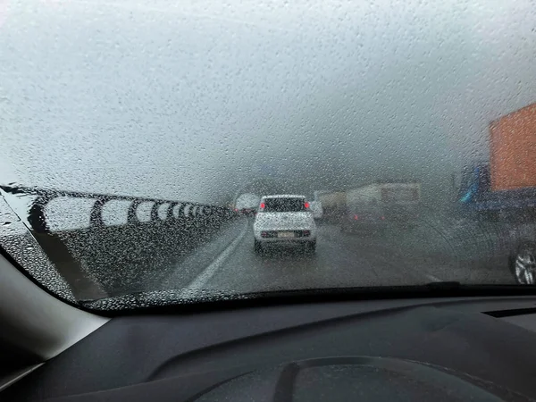 Intense traffic on the highway on a foggy rainy day. Raindrops on the windshield. Ascent of the mountain range on the Imigrantes highway near the city of Sao Paulo - Brazil