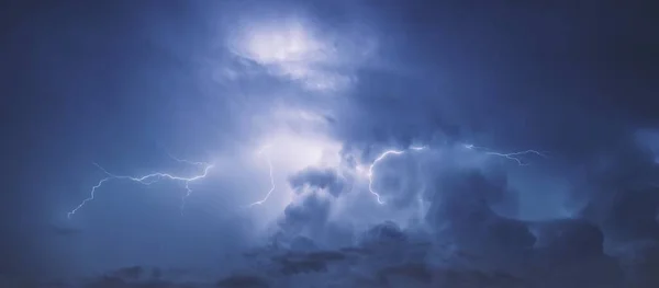 Lightning in the blue sky with clouds at night.