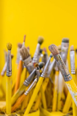 Set of paint brushes with yellow handle seen close up. Selective focus and yellow background.