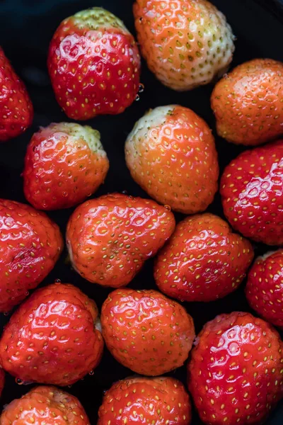 Strawberries in water with bubbles. Black background.