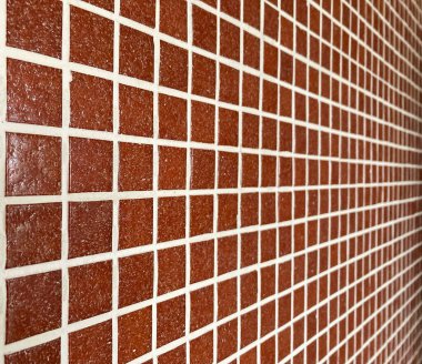 Wall coated with red glass tiles in perspective. Selective focus.