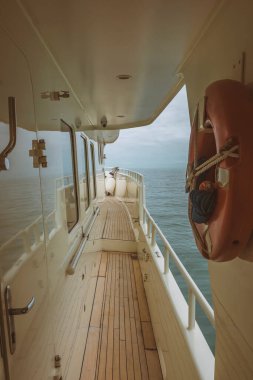 Yat denizde yüzüyor. Güverte ve geminin yan tarafında. Mavi gökyüzü ve bulutlarla Ufuk.