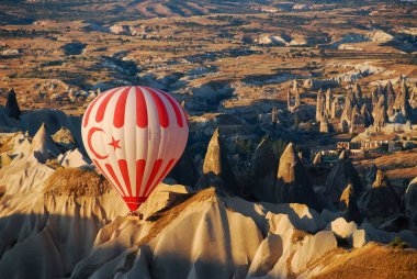 Sıcak hava balonu, Kapadokya, Türkiye. Beyaz ve kırmızı balonlu ay ve Türk bayrağı şafakta bölgede dalgalanacak. Volkanik rahatlama detayları, bölgenin simgesi..
