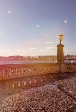 Santos şehri, Brezilya. Plajın kenarında eski bir sokak lambası olan geleneksel şehir duvarı. Ponta da Praia bölgesinde gün batımı.