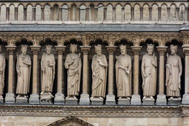 Notre Dame Katedrali, Paris, Fransa. Ön cephenin ayrıntıları. Kralların, azizlerin ve rahiplerin heykelleri, kılıçlar, haçlar, kozalaklar ve diğer semboller.. 