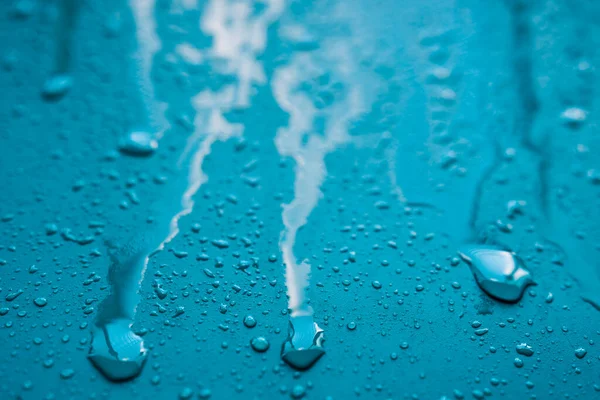 Damp blue surface with dripping water drops.