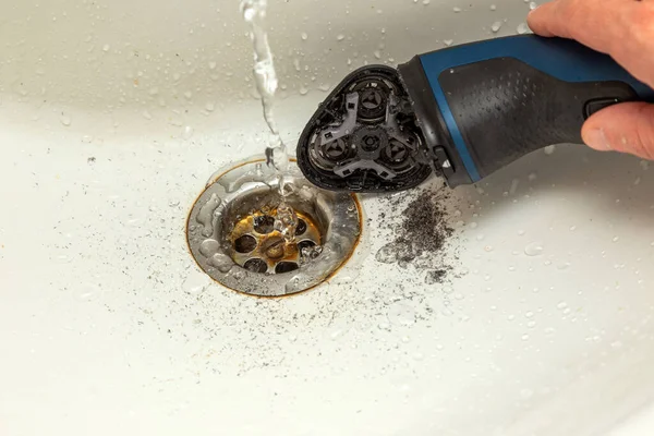 cleaning the rotary electric shaver from stubble under the water jet