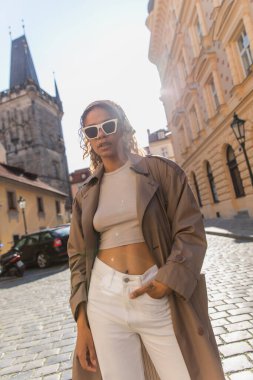 stylish african american woman posing near old town hall tower in prague
