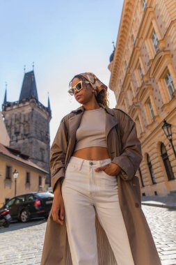low angle view of african american woman posing near old town hall tower in prague clipart