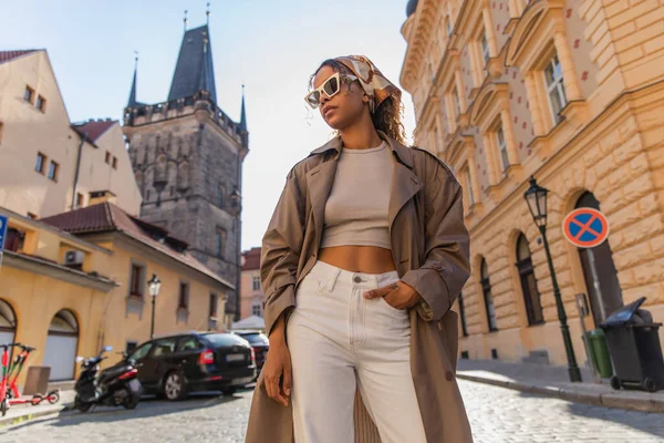 Низкий угол зрения на стильный африканский американец женщина позирует возле старой башни ратуши в Праге — стоковое фото
