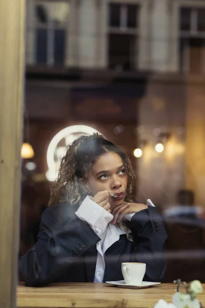 Стильна афроамериканська жінка їсть піну з чашки капучино в кафе — стокове фото