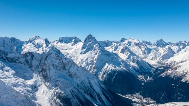Kafkasya Dağları, Belalakaya, Sofrudzhu ve Sulakhat dağları ile kayak yamacının panoramik manzarası kış günü ufukta. Dombai kayak merkezi, Batı Kafkasya, Karachai-Cthe, Rusya.
