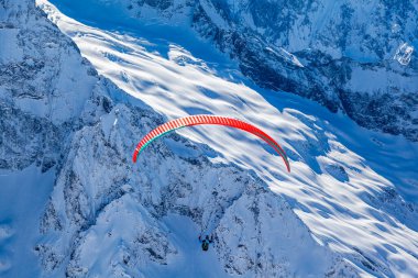 Dağlarda yamaç paraşütü yapan insanlar kışın Dombay kayak merkezinde dağın tepesinde yamaç paraşütü yapıyorlar. Aktif yaşam tarzı ve ekstrem spor macerası kavramı.