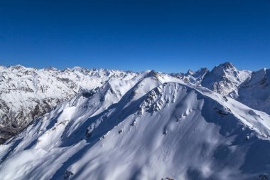 Kafkasya Dağları, Belalakaya, Sofrudzhu ve Sulakhat dağları ile kayak yamacının panoramik manzarası kış günü ufukta. Dombai kayak merkezi, Batı Kafkasya, Karachai-Cthe, Rusya.