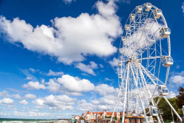 Mavi gökyüzünün arka planında dönme dolap, lunapark, çocuklarla tatil