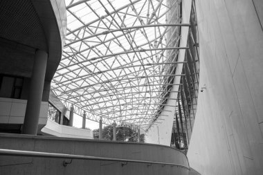 Binaların modern mimarisi, metal yapıların detaylarındaki soyutlama, cam ve beton. Çağdaş çehrenin eğri köşegen çizgileri üzerinde soyut gölgeler ve ışık deseni. Cam bina cephesinin bir parçası, B & W