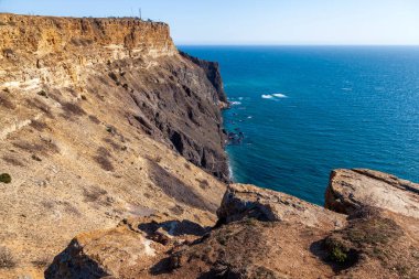 Kırım 'daki Karadeniz kıyısı, Sivastopol' daki Cape Fiolent manzarası. Panoramik deniz manzarası, sakin gök mavisi deniz, bulutlar ve parlak gökyüzü..