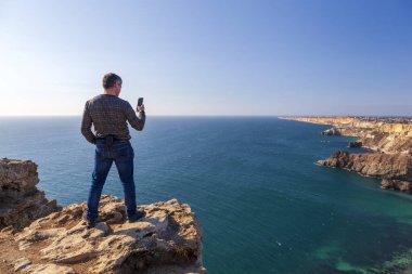 Kırım 'daki Karadeniz kıyısı, Sivastopol' daki Cape Fiolent manzarası. Panoramik deniz manzarası, sakin gök mavisi deniz, bulutlar ve parlak gökyüzü..