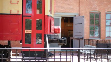 Red and vanilla colored train in front of museum.