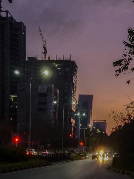 A sunset in Islamabad with a skyscraper under construction in the background.
