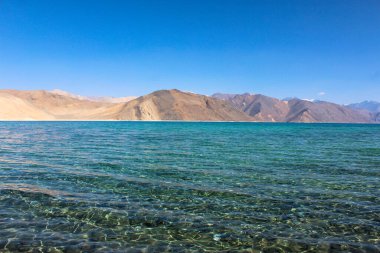 The world's highest saltwater lake named Pangong Tso. Its water, which seems to be dyed in blue, stand in stark contrast to the arid mountains surrounding it