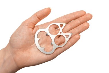 In a woman's hand is a miniature brass knuckles in the form of a cat's head, as well as a bottle opener. Isolated on white background.