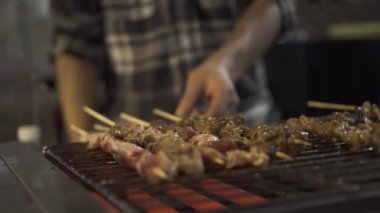 Hong Kong şefi kebap yapıyor ve ızgaraya sos serpiyor.