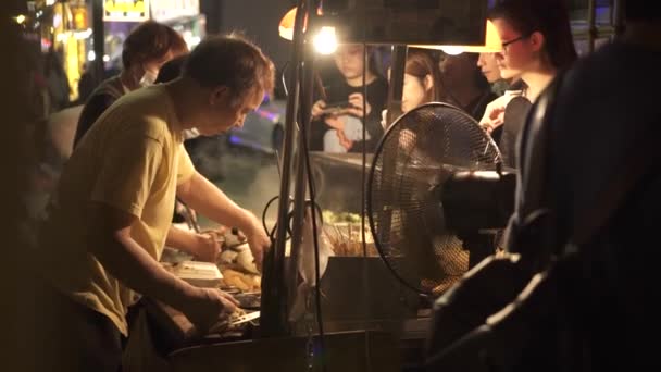 Gammal asiatisk man lagar mat på gatan café på kvällen — Stockvideo