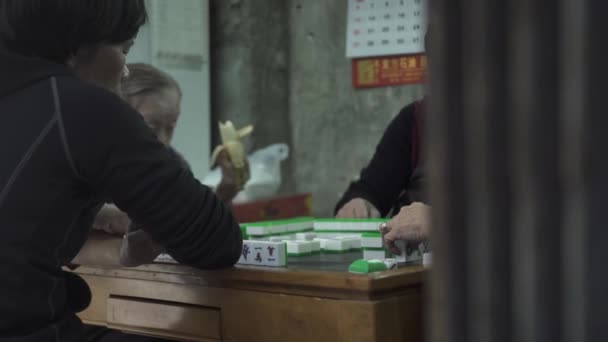 Asiáticos juegan mahjong sentado en la mesa de madera en la habitación — Vídeos de Stock