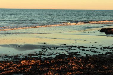 Reflections in the wet sand during sunset on a Mediterranean beach