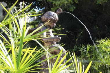 Fountain with a bronze statue of a child, among bamboos.