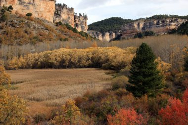 Multicolored landscape in autumn, next to the Ua lagoon, under steep mountains in the mountains of Cuenca. Castilla La Mancha. Spain