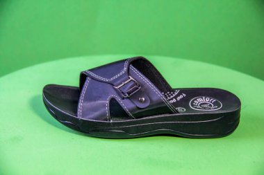 Illustrative Editorial branded photography, Slipper shouted on green Background, shot is selective focus with shallow depth of field. Photos taken at Cairo Egypt on 28 March 2019