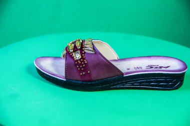 Illustrative Editorial branded photography, Slipper shouted on green Background, shot is selective focus with shallow depth of field. Photos taken at Cairo Egypt on 28 March 2019