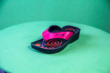 Illustrative Editorial branded photography, Slipper shouted on green Background, shot is selective focus with shallow depth of field. Photos taken at Cairo Egypt on 28 March 2019