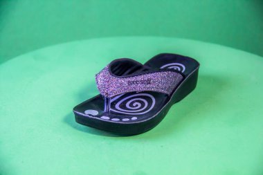 Illustrative Editorial branded photography, Slipper shouted on green Background, shot is selective focus with shallow depth of field. Photos taken at Cairo Egypt on 28 March 2019