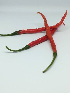 three red chilies on a white background