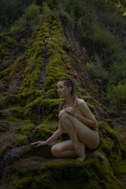 Beautiful woman near moss waterfall