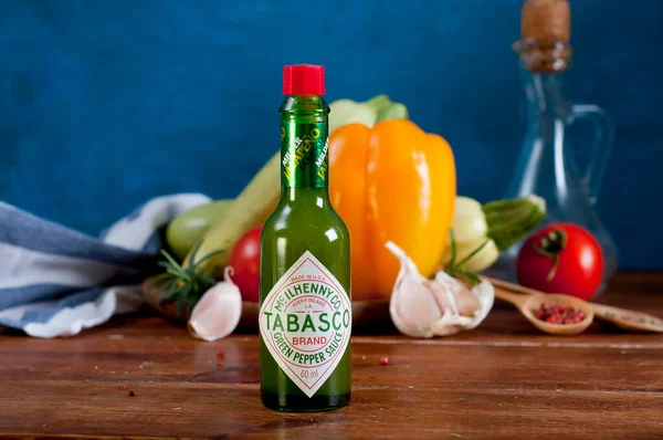 bottle of tomato sauce with spices and herbs on wooden table