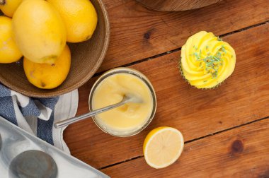 Lemon homemade cupcake with yellow whipped cream on wooden table