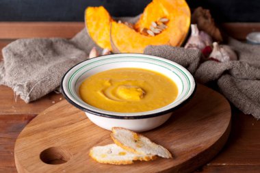 hot spice pumpkin soup with garlic, chili pepper, ginger on wooden table