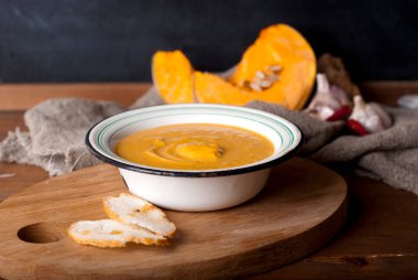 hot spice pumpkin soup with garlic, chili pepper, ginger on wooden table