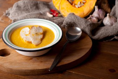 hot spice pumpkin soup with garlic, chili pepper, ginger on wooden table
