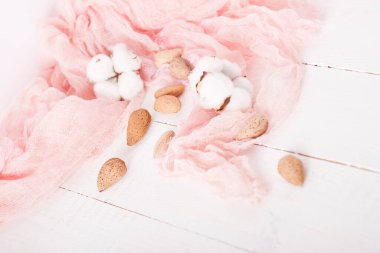 almonds and cotton with rose textile on whte wooden table
